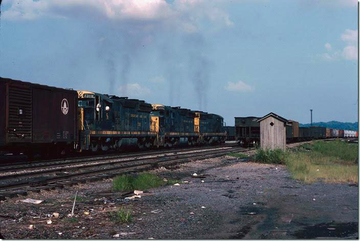 SD18s 7318-7310-7311 slowly shove freight cars across the westbound manifest hump. It must be a boring job, but the crew works a regular shift and gets paid well. The Fitzpatrick hump was later leveled, and the yard is now used for tank car storage. That outhouse is located in a convenient location! Russell '76-77.