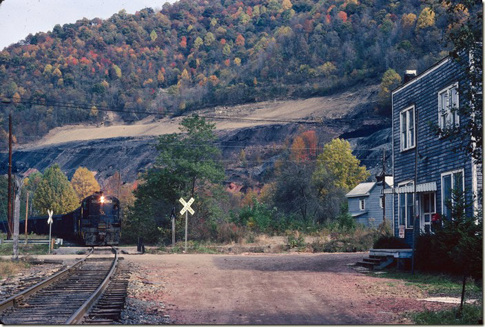 A westbound mine run comes down the Buffalo SD at Robinette WV, past the post office. C&O 5863-6013 power one of several mine runs that will be needed daily to work all of the mines on Buffalo Creek. Note the “red dog” spread out as road material. “Red dog” was slate that was the result of spontaneous combustion in coal refuse dumps...like the one in the background being reclaimed. It makes excellent secondary road material. The structure was probably a company store/office at one time. 10-24-1977. C&O Logan, Buffalo, IC SD.