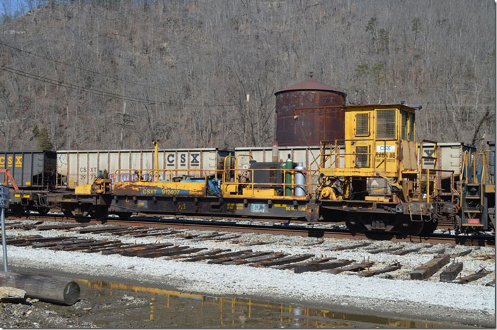 CSX MW flat 912407 with rail unloader RAUN #6. In the background is the only steam-era support structure left at Shelby...the water tank. Shelby KY.
