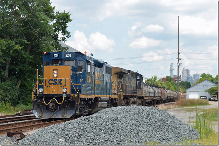 CSX 2034-110 wait at Butler Street in Hamilton OH with a s/b train of mostly steel coil flats.