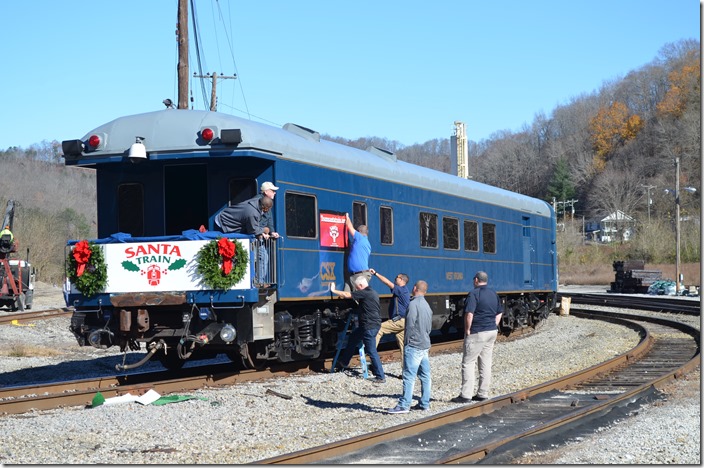 Volunteers hanging Santa Train banner on CSX bus car 994310 West Virginia. View 2.