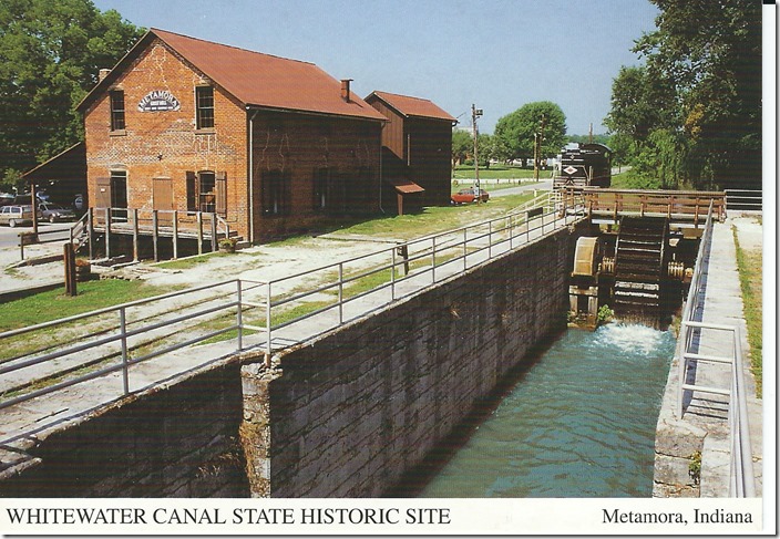 The grist mill was built in 1845 at Lock 25. It uses water from the canal to power its machinery. Mill operation is presently powered by a “breast” wheel housed in the lock. Whitewater Valley’s Lima 750 HP switcher is parked in the background. Whitewater Canal SHS card.